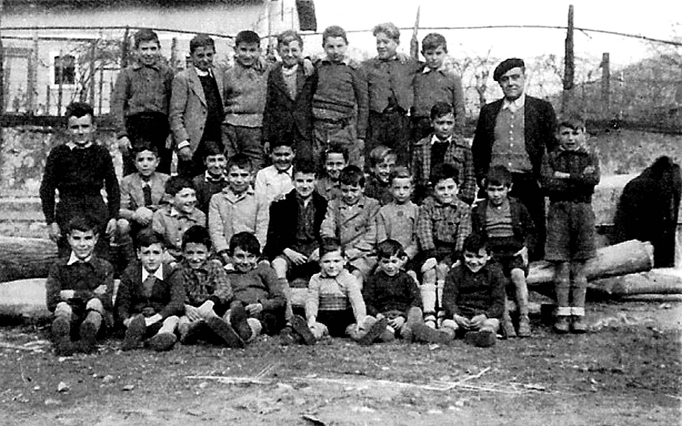 1945eko Berriatuko eskolako mutikoen taldeko argazkia, irakaslearekin. Atzean Martin-enea etxea. [Argazkia]